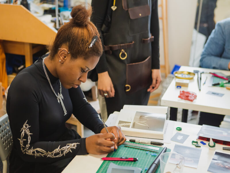 A woman in a black shirt concentrates as she works on a jewellery project